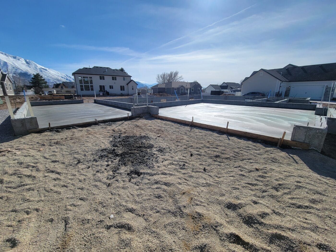 A construction site with a lot of dirt and a house in the background.