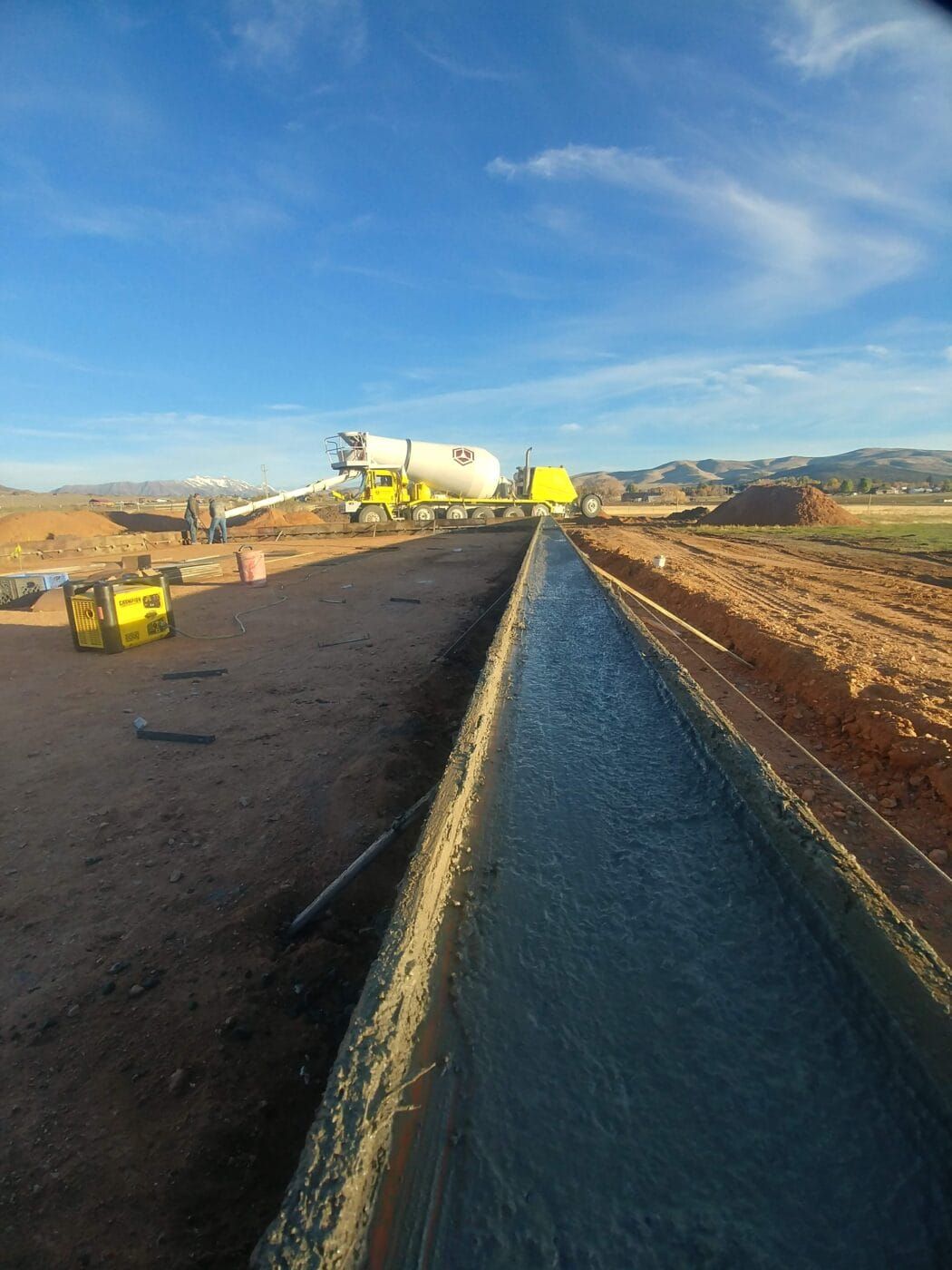 A concrete truck is pouring concrete on a road.