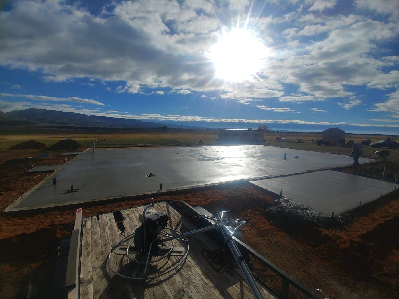 A concrete floor is being built in a field with the sun shining through the clouds.