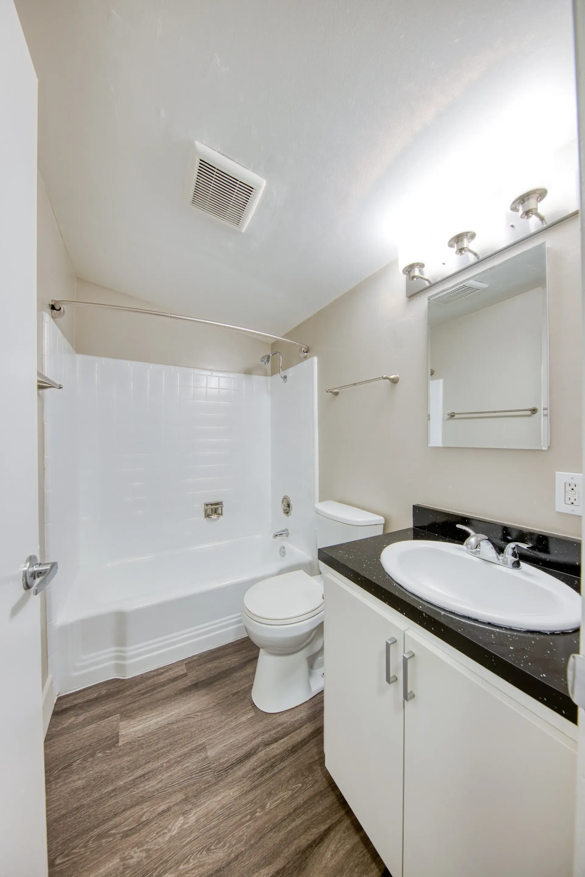 Bathroom with a shower/tub combo, toilet, and vanity with a sink.