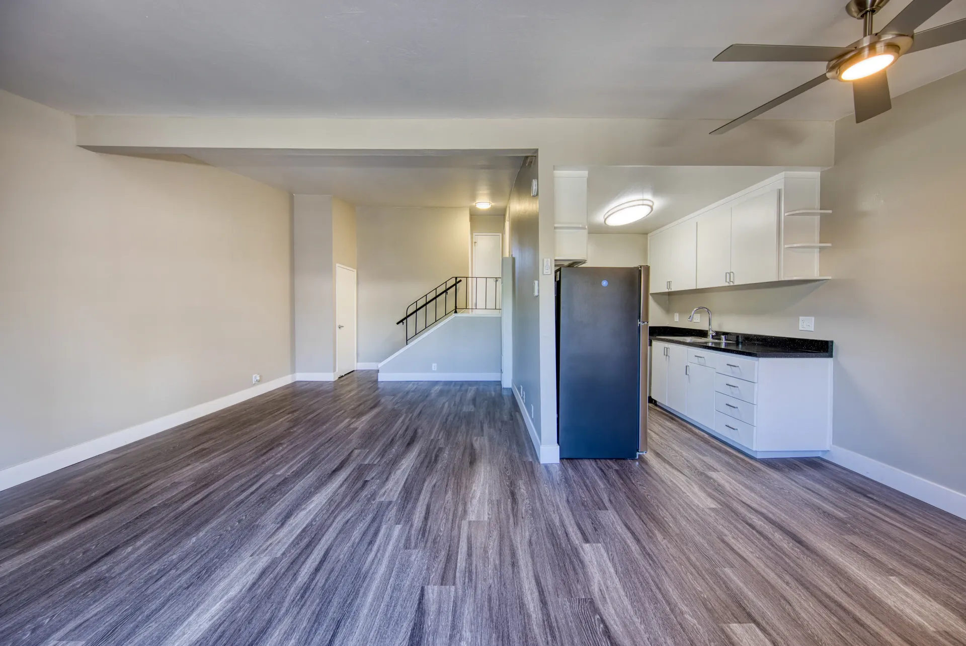 Interior view of an empty apartment living room and kitchen area with stairs.