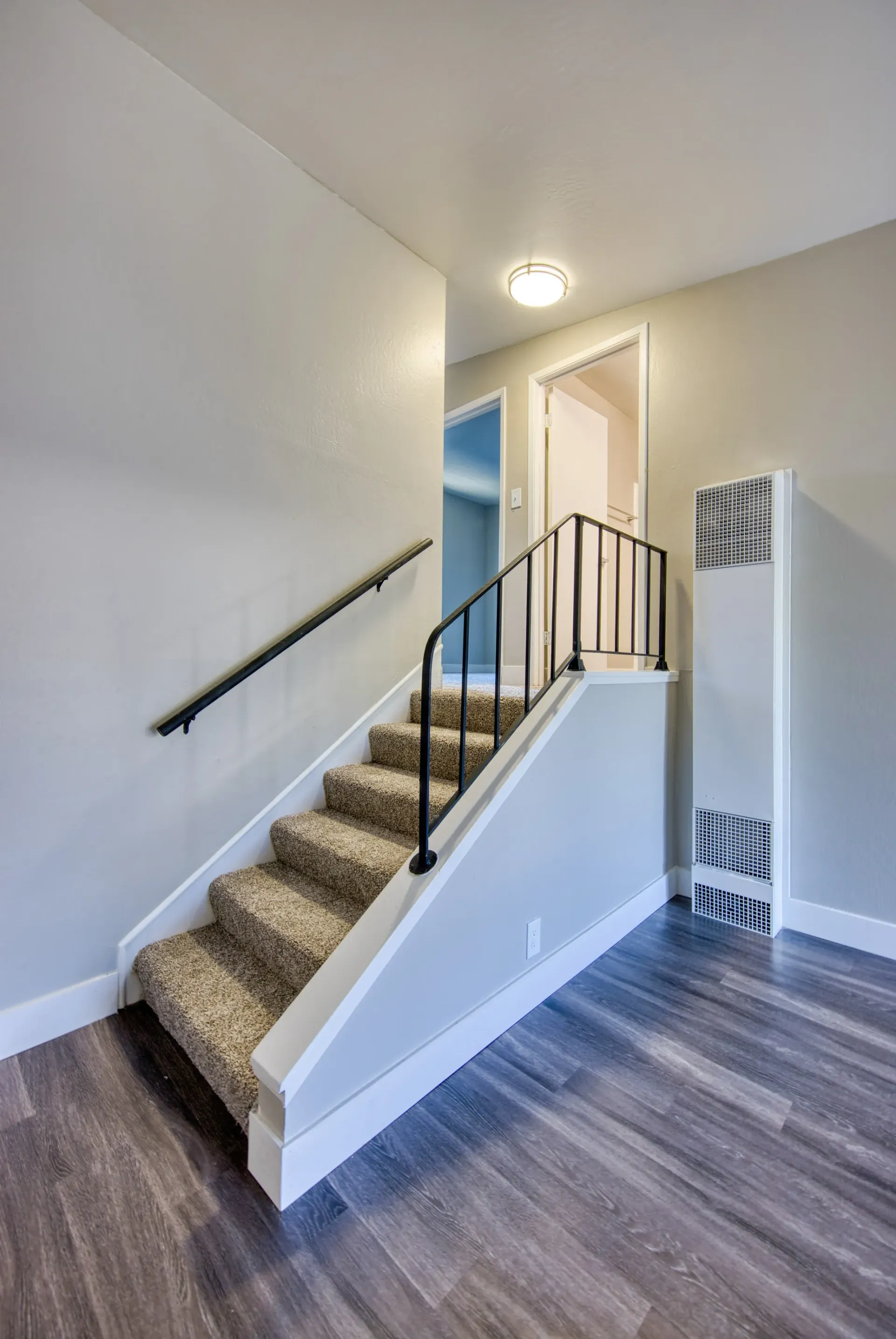 Interior staircase with carpeted steps and black railing.