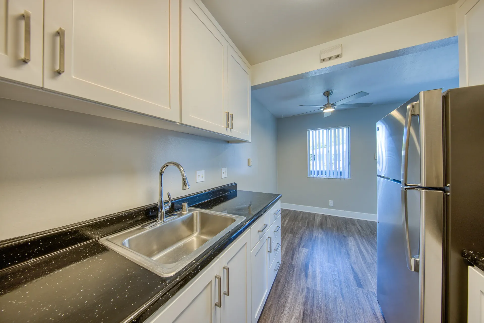 Modern kitchen with white cabinets, black granite countertops, and stainless steel appliances.