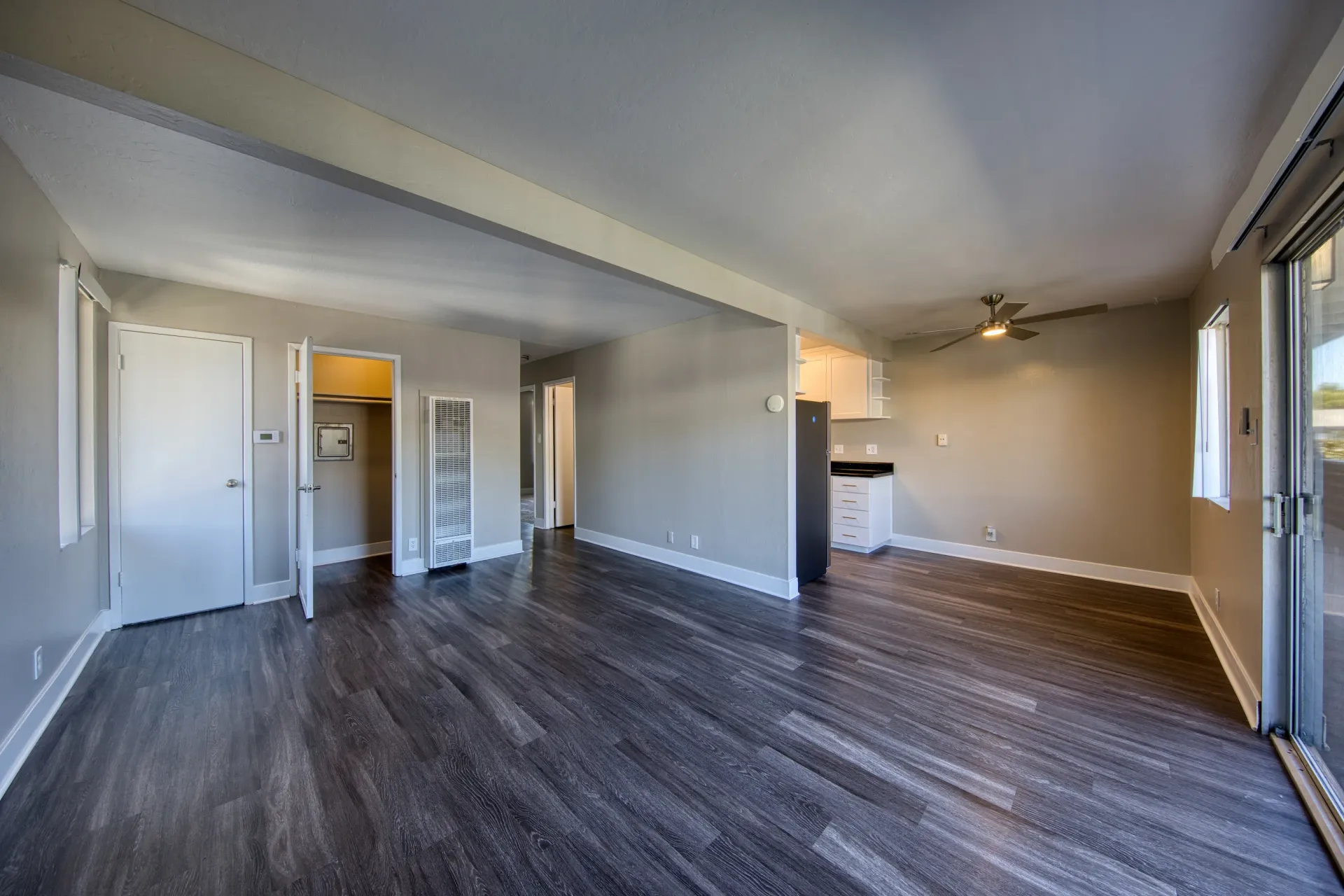 Spacious living area with modern dark wood flooring and access to a balcony.
