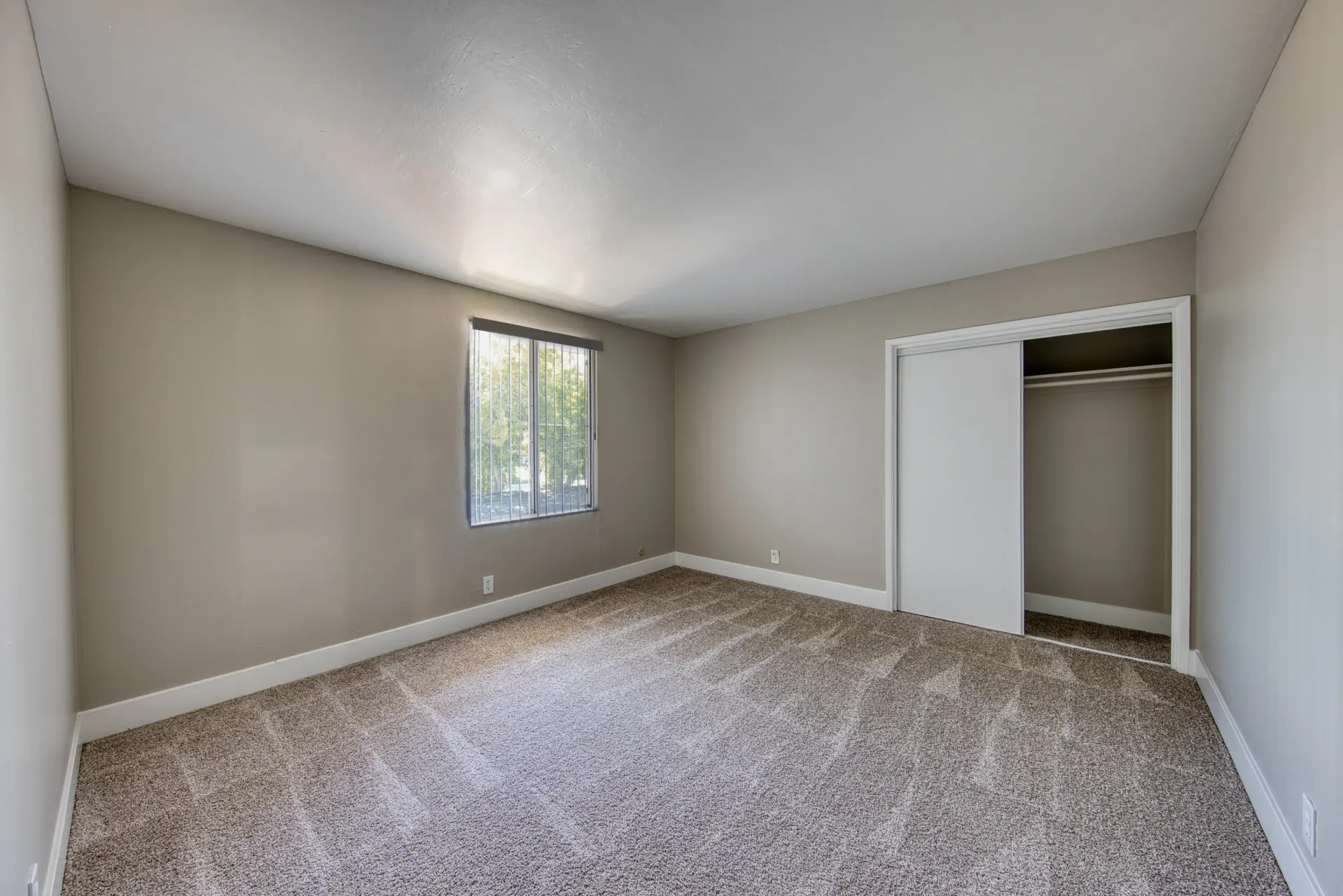 Bedroom with beige carpet and sliding closet doors.