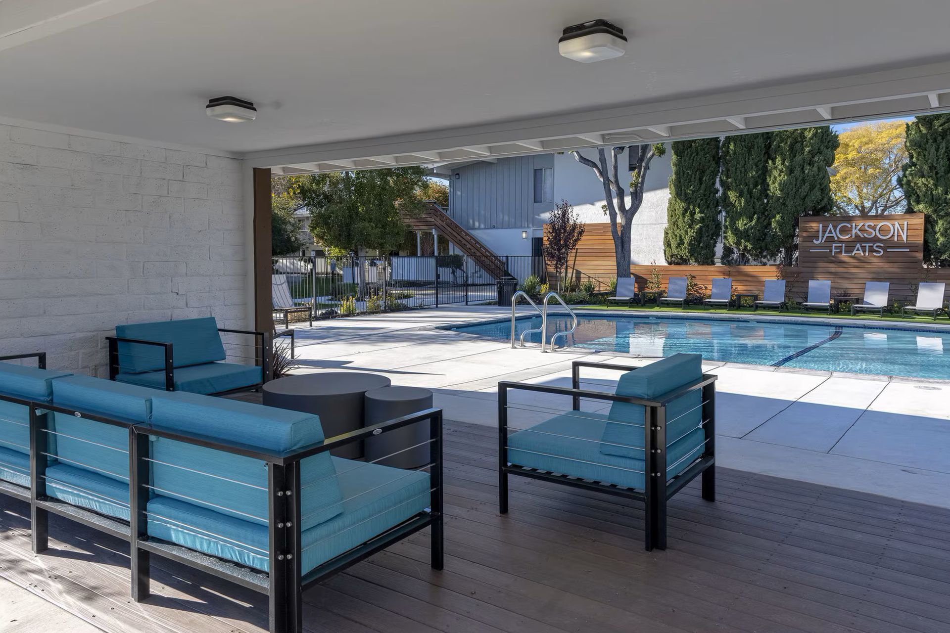 Covered patio with blue seating overlooking an outdoor pool area.