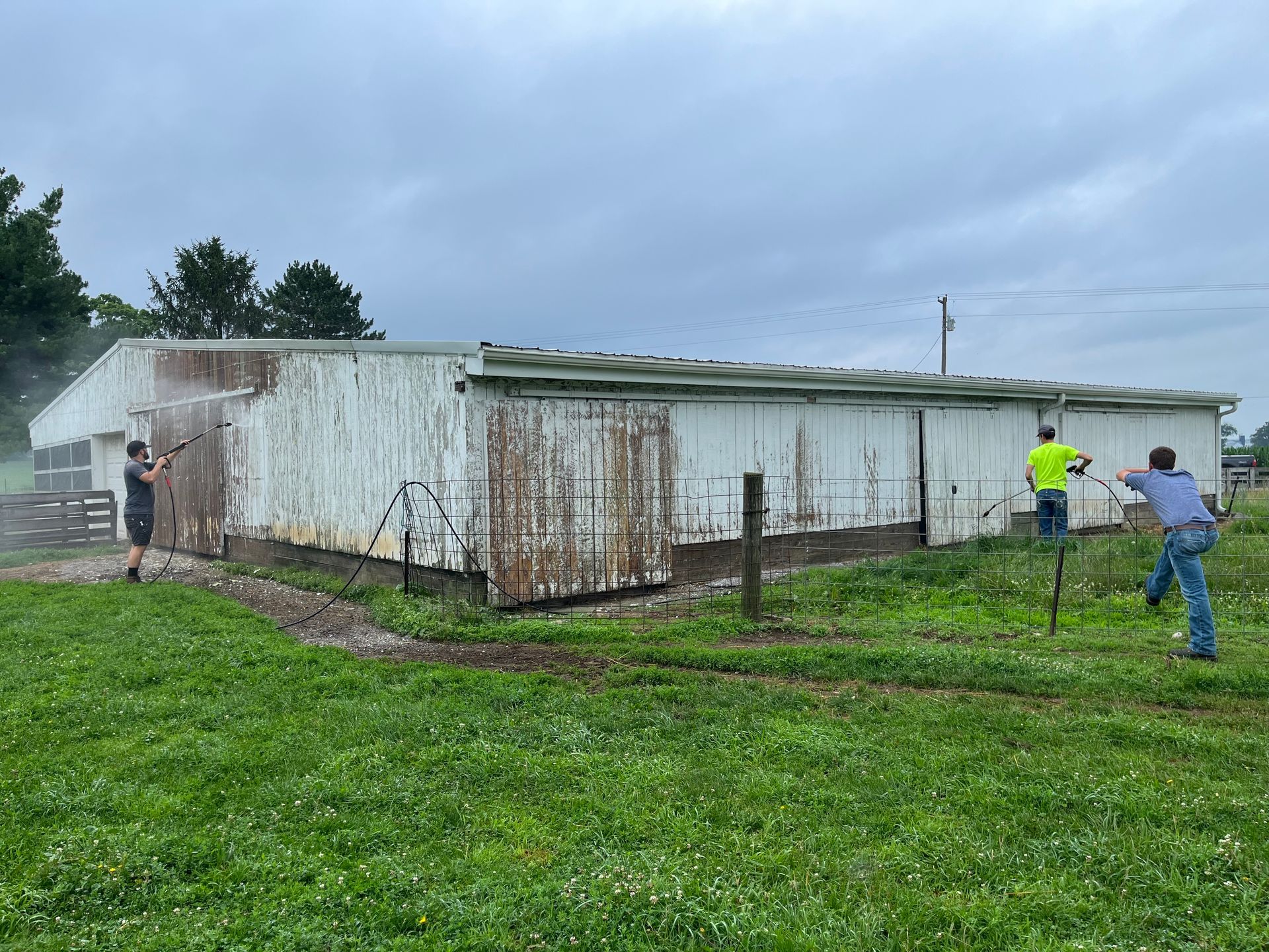 A group of people are painting a white building in a field.