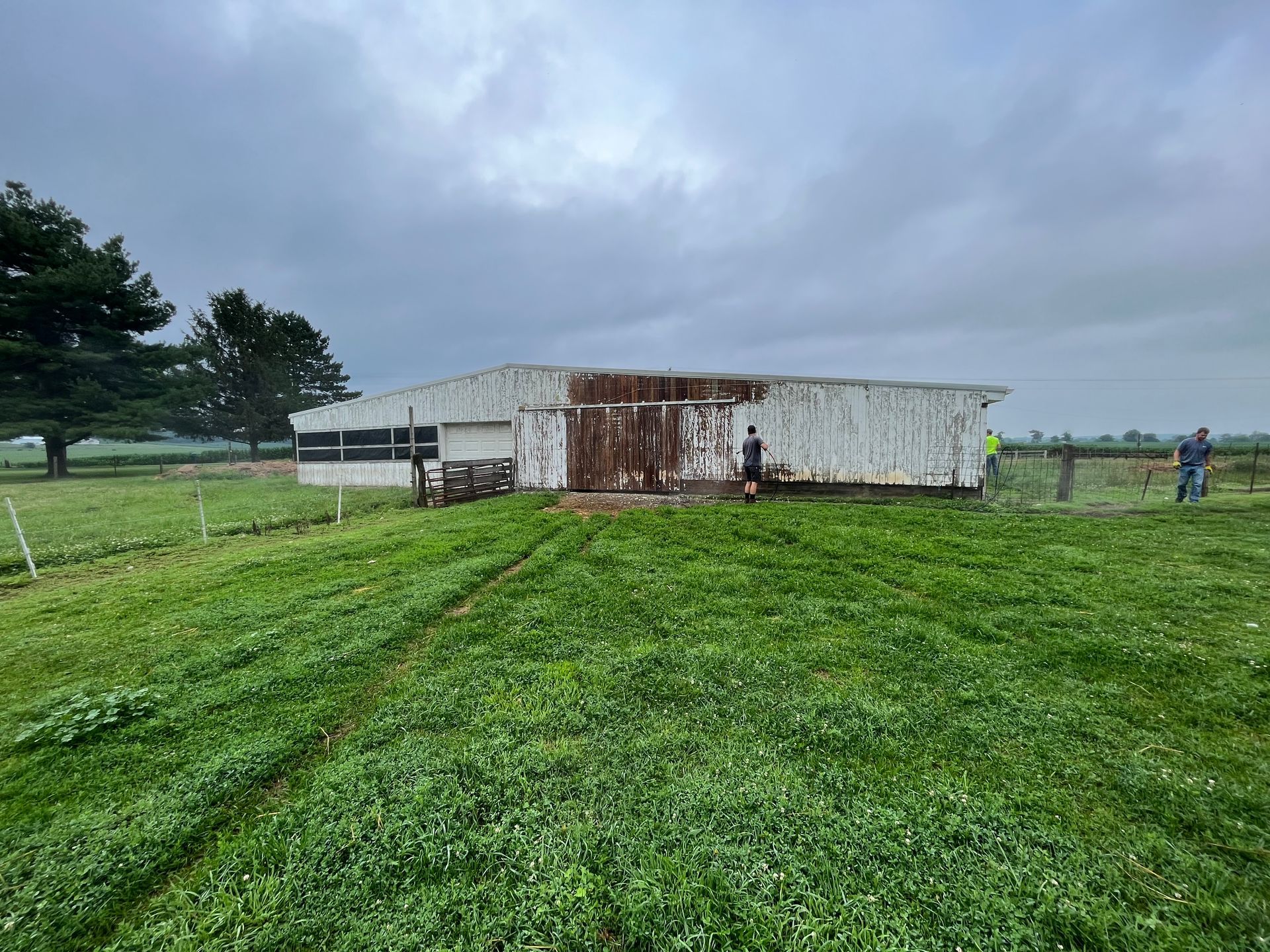 A white building is sitting in the middle of a grassy field.