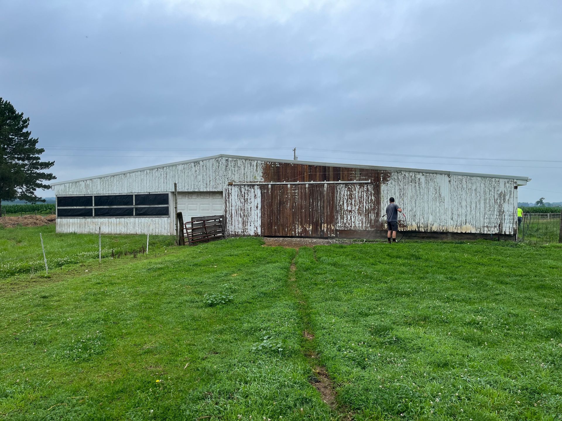 A man is standing in front of a white building in a grassy field.