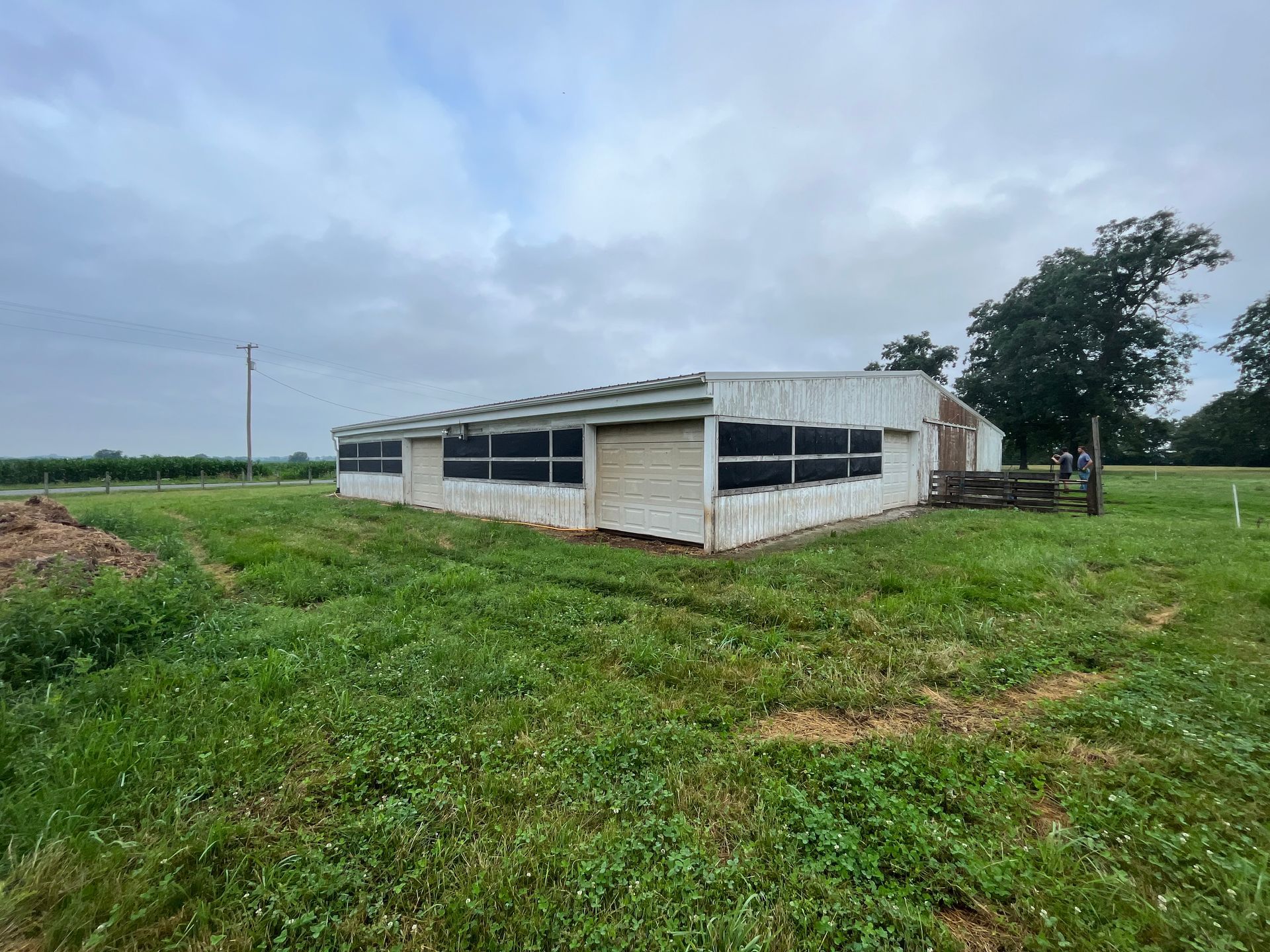 A white building is sitting in the middle of a grassy field.