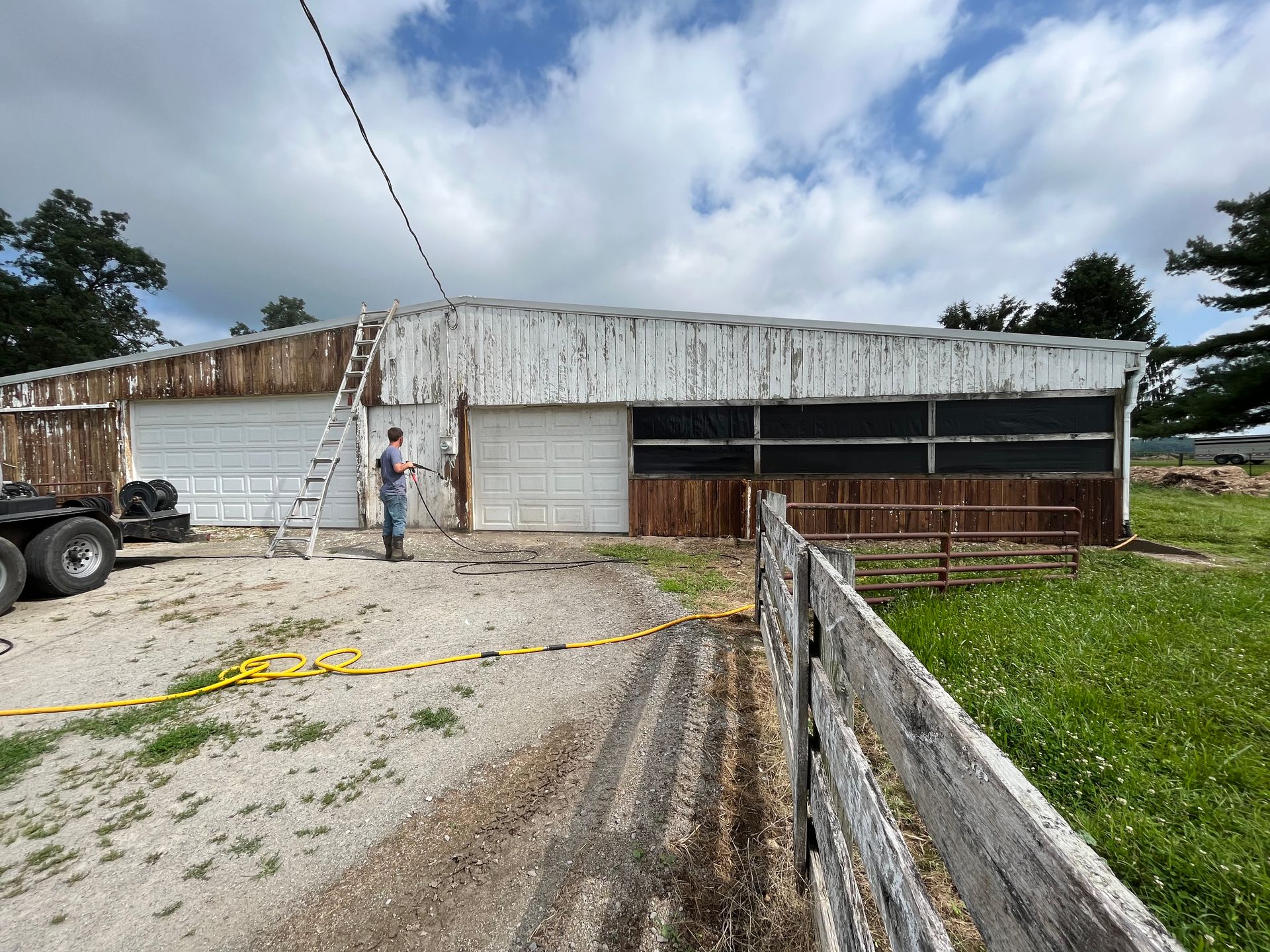 A man is standing in front of a barn with a ladder.