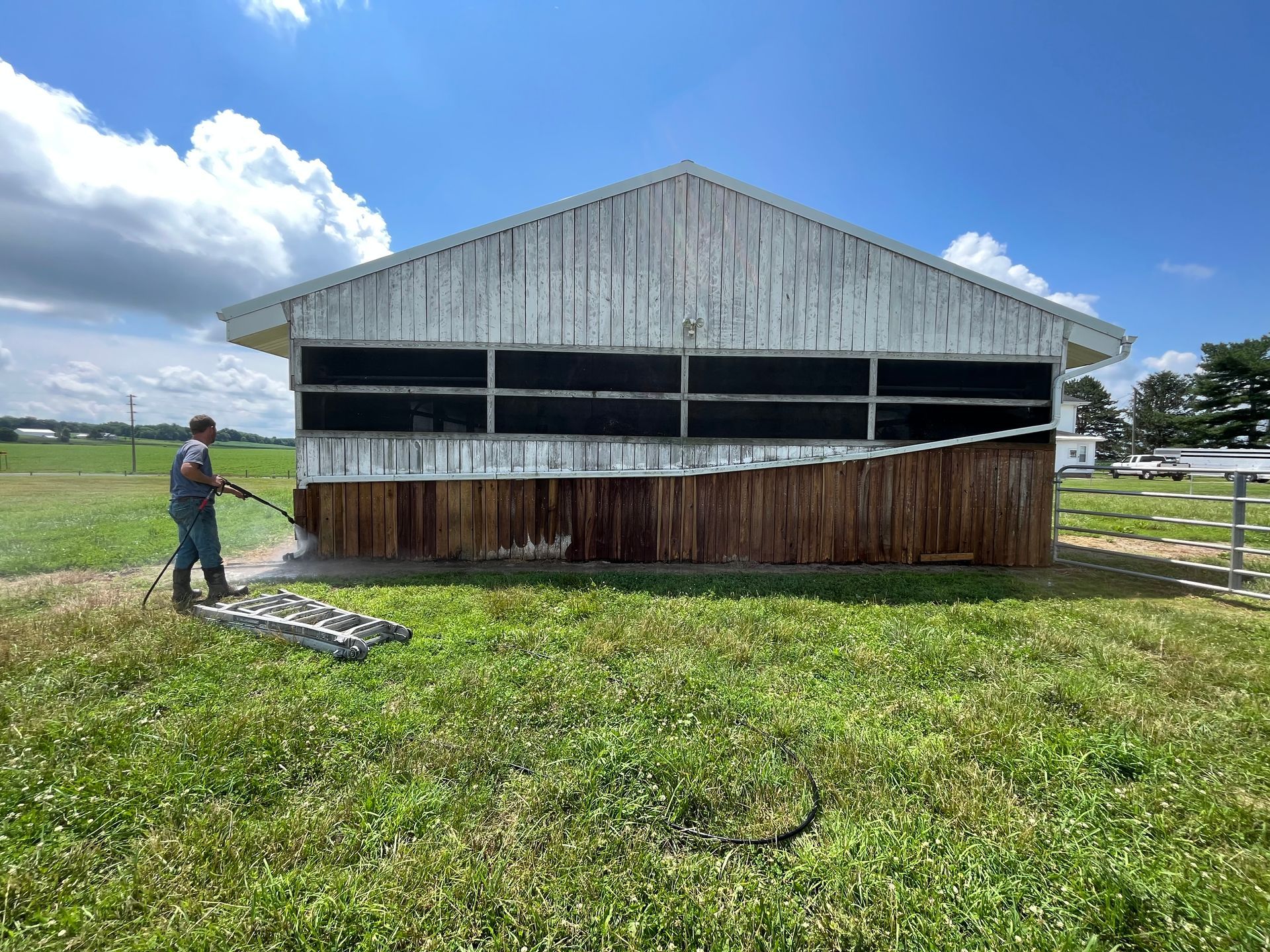 A man is standing in front of a barn in a field.