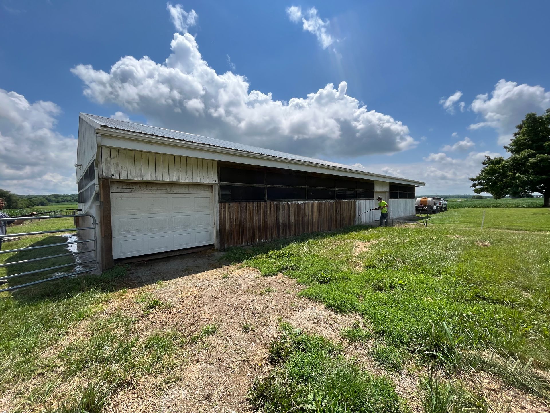 A white barn is sitting in the middle of a grassy field.