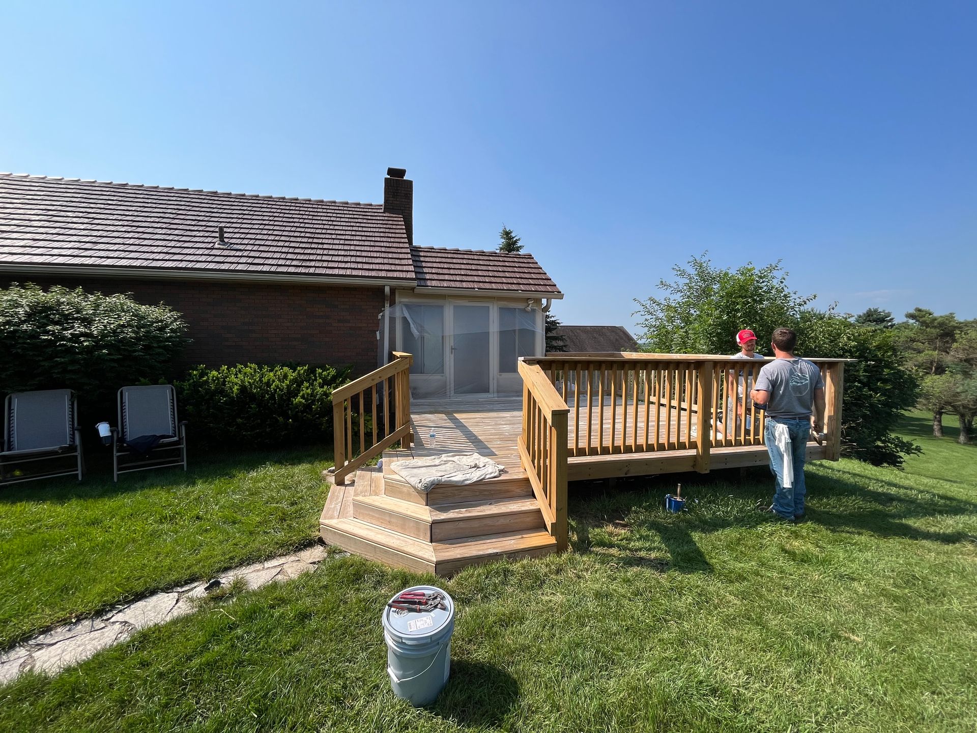 A man is standing on a wooden deck in front of a house.
