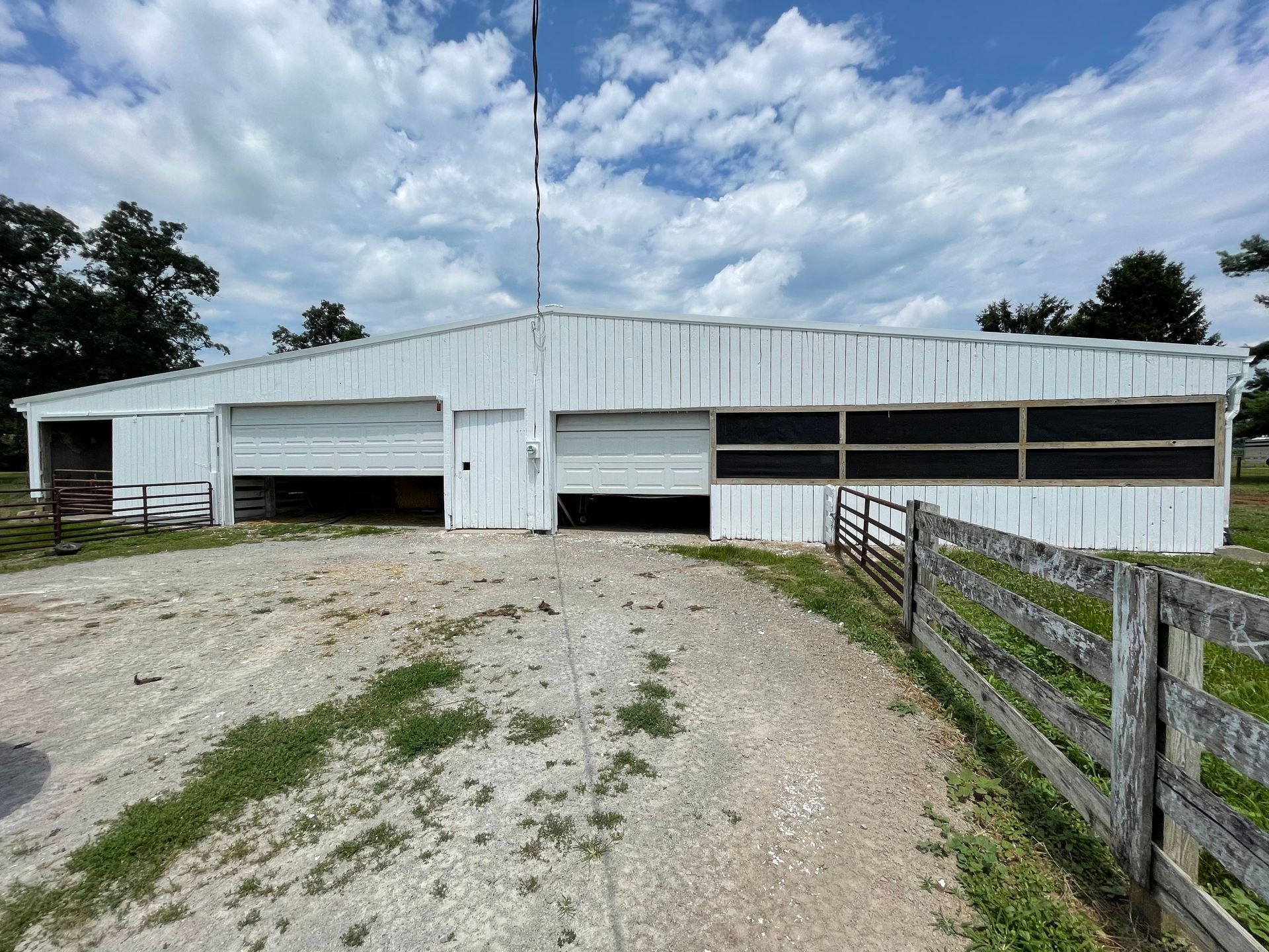 A large white barn with a wooden fence in front of it.