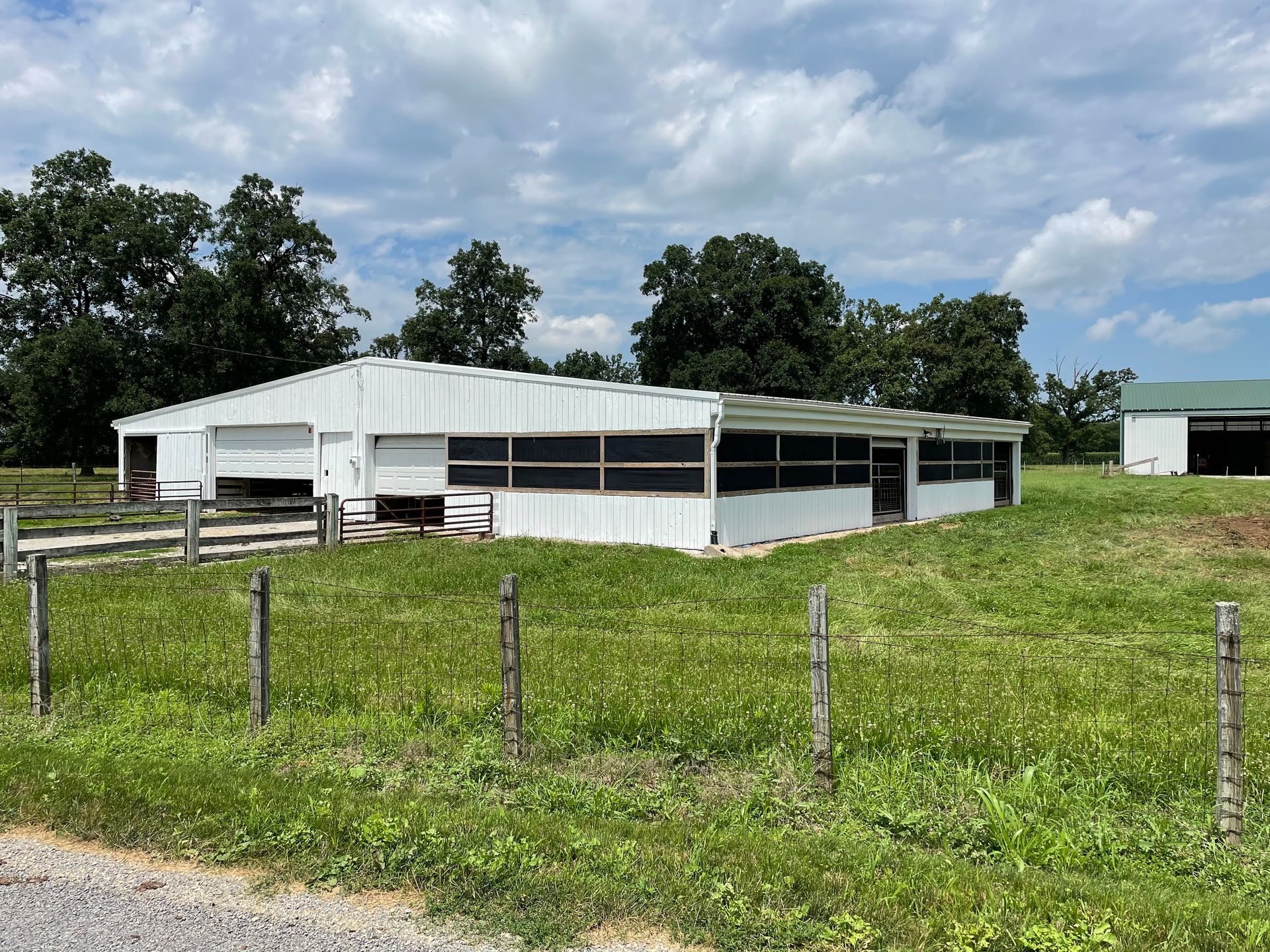 A large white building is sitting in the middle of a grassy field.