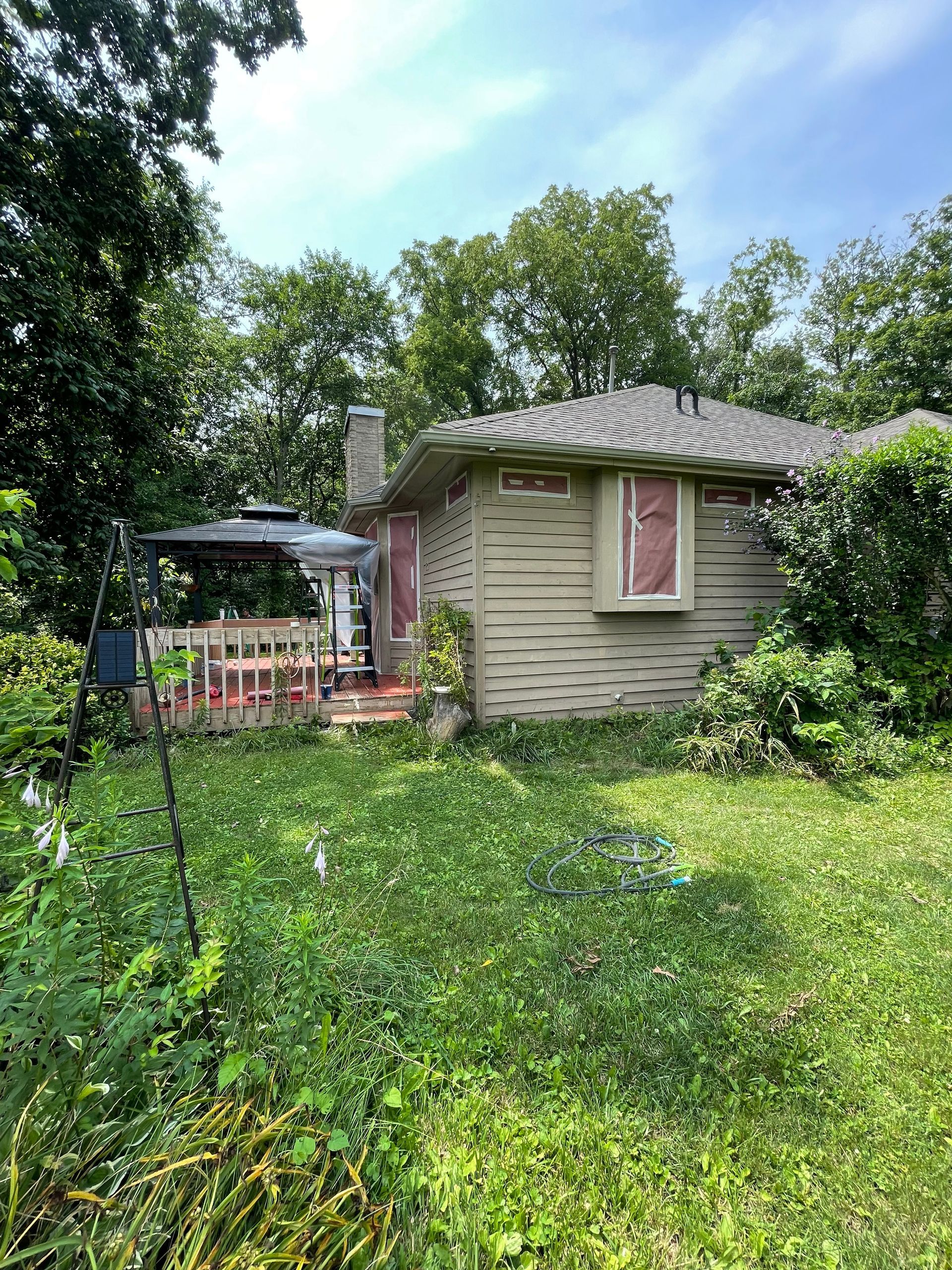 A small house is sitting in the middle of a lush green yard surrounded by trees.