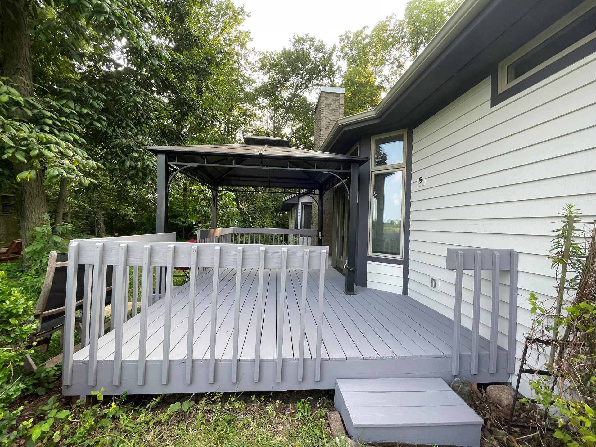 A white house with a gray deck in front of it.