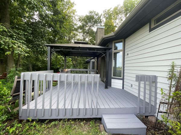 A white house with a gray deck in front of it.