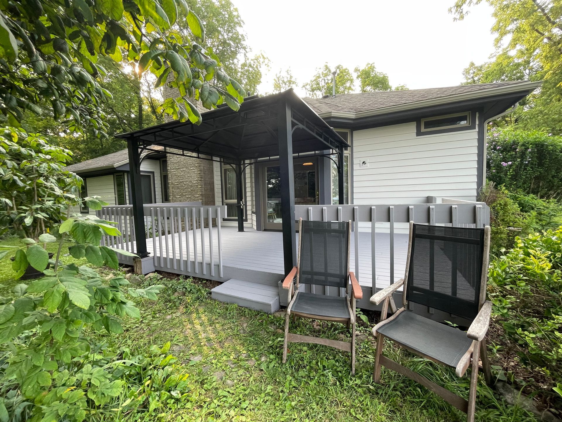 A small house with a porch and chairs in front of it.
