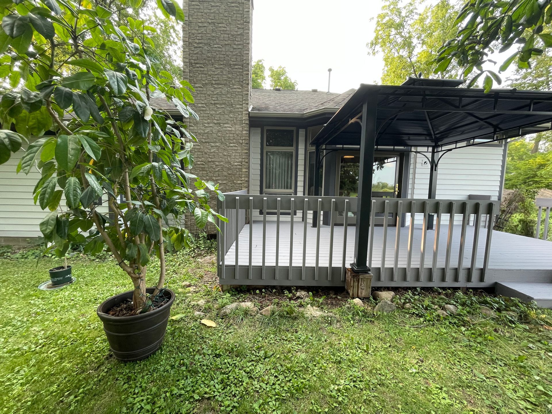 A potted plant is sitting in front of a house with a deck.