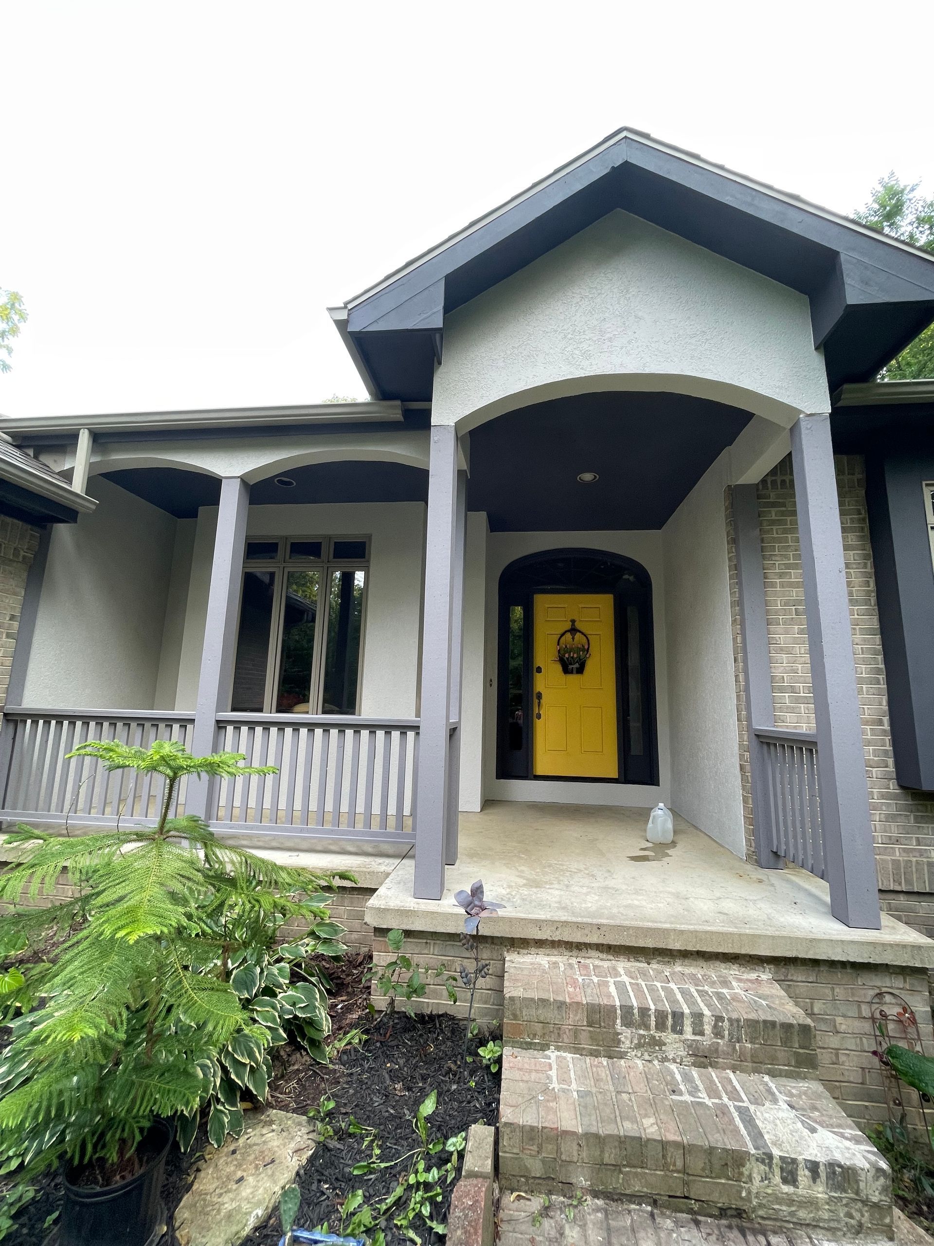 The front of a house with a yellow door and a porch.