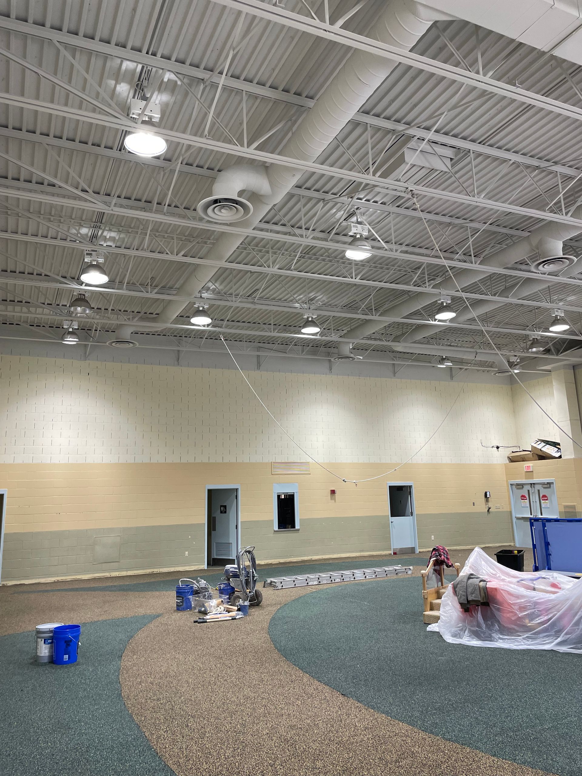 A large empty room with a carpeted floor and a ceiling.