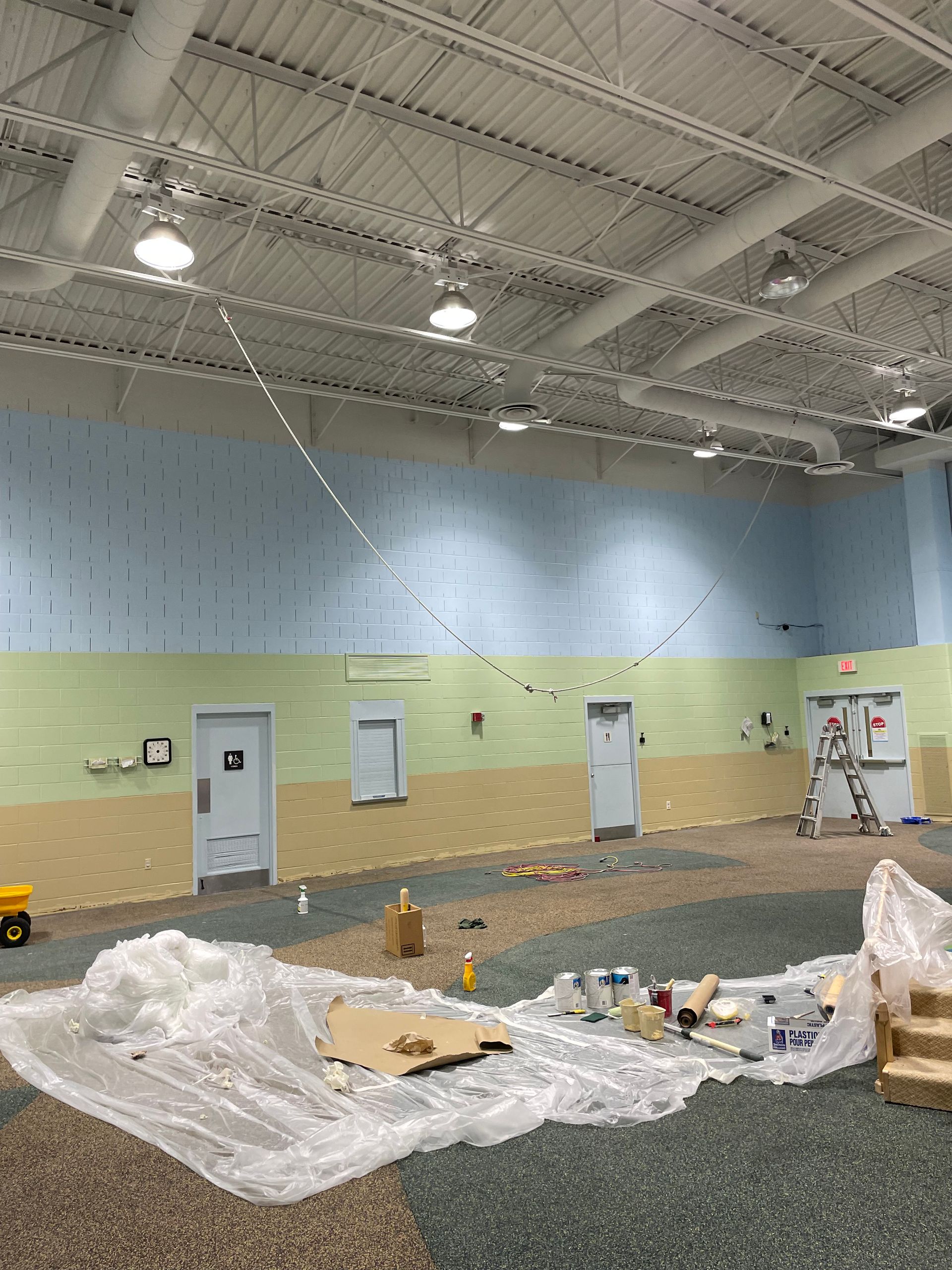A large room with a ceiling that is being painted.
