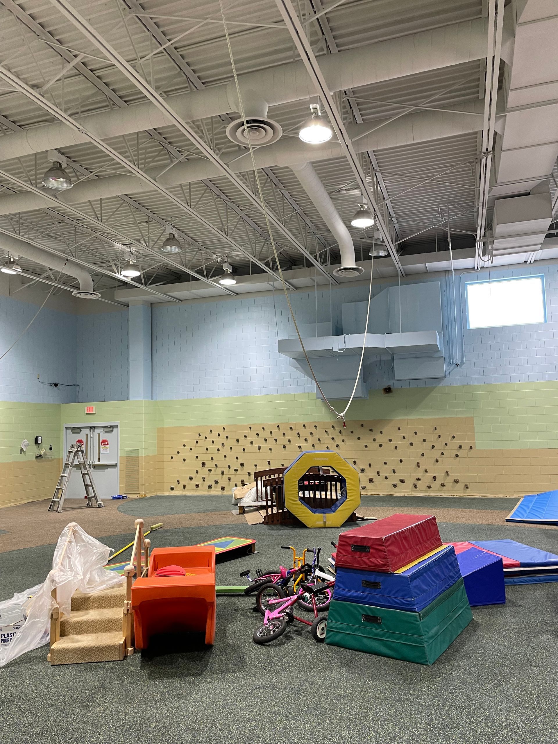 A large indoor gym with a lot of toys on the floor.
