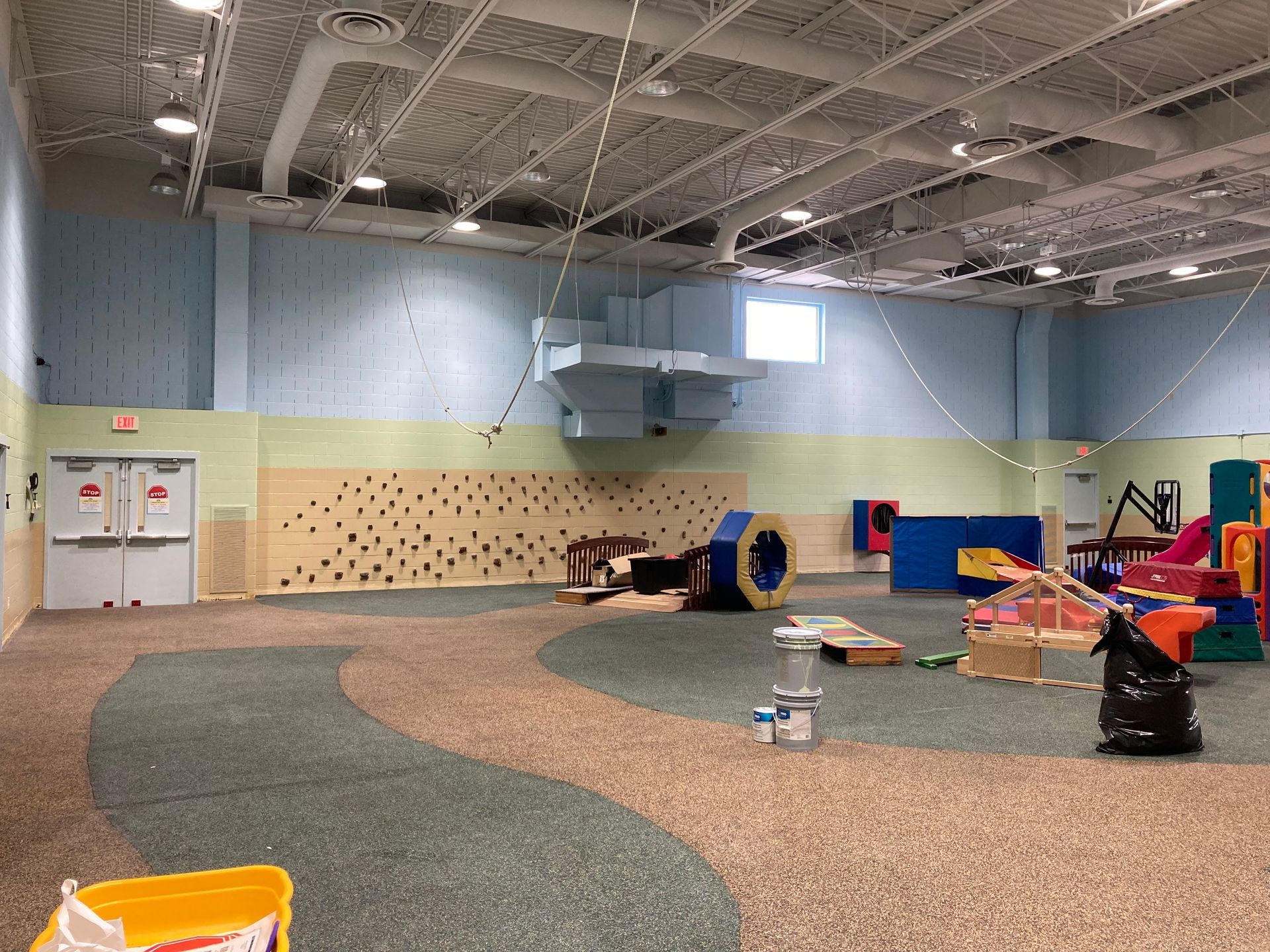 A large room with a lot of toys and a climbing wall.