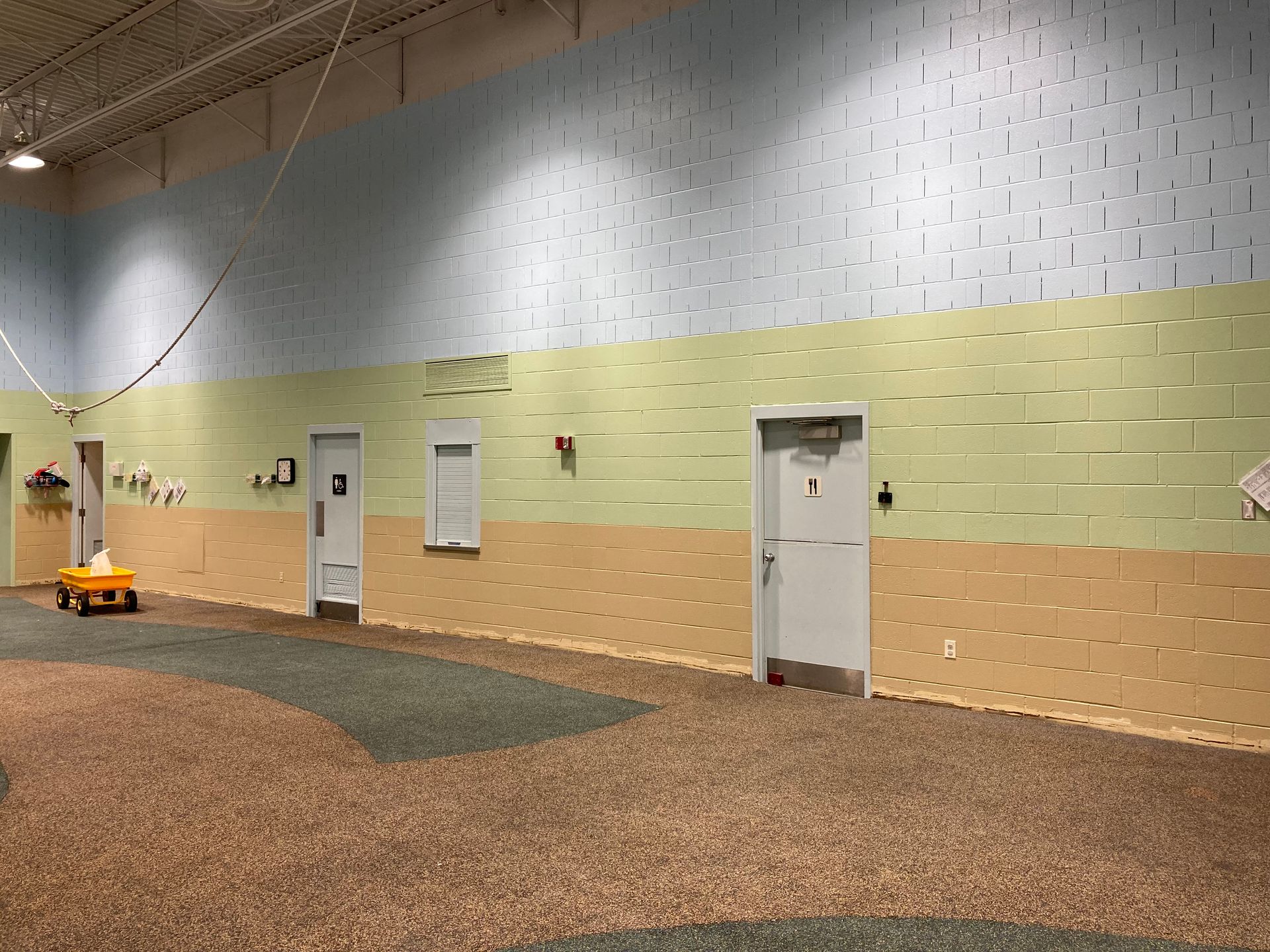 A large empty room with a yellow toy car in the middle of it.
