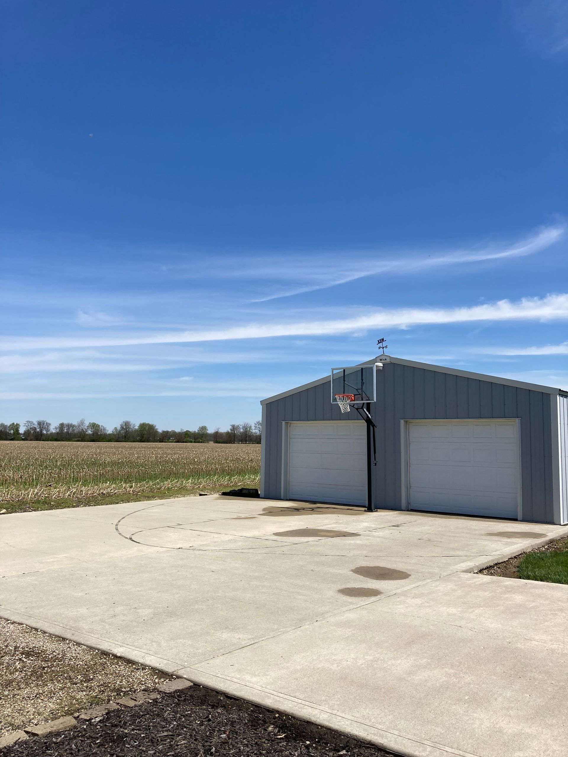 A garage with two garage doors and a basketball hoop on top of it.