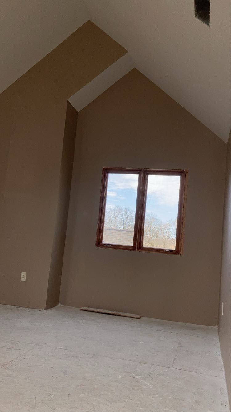 An empty room with a vaulted ceiling and two windows.
