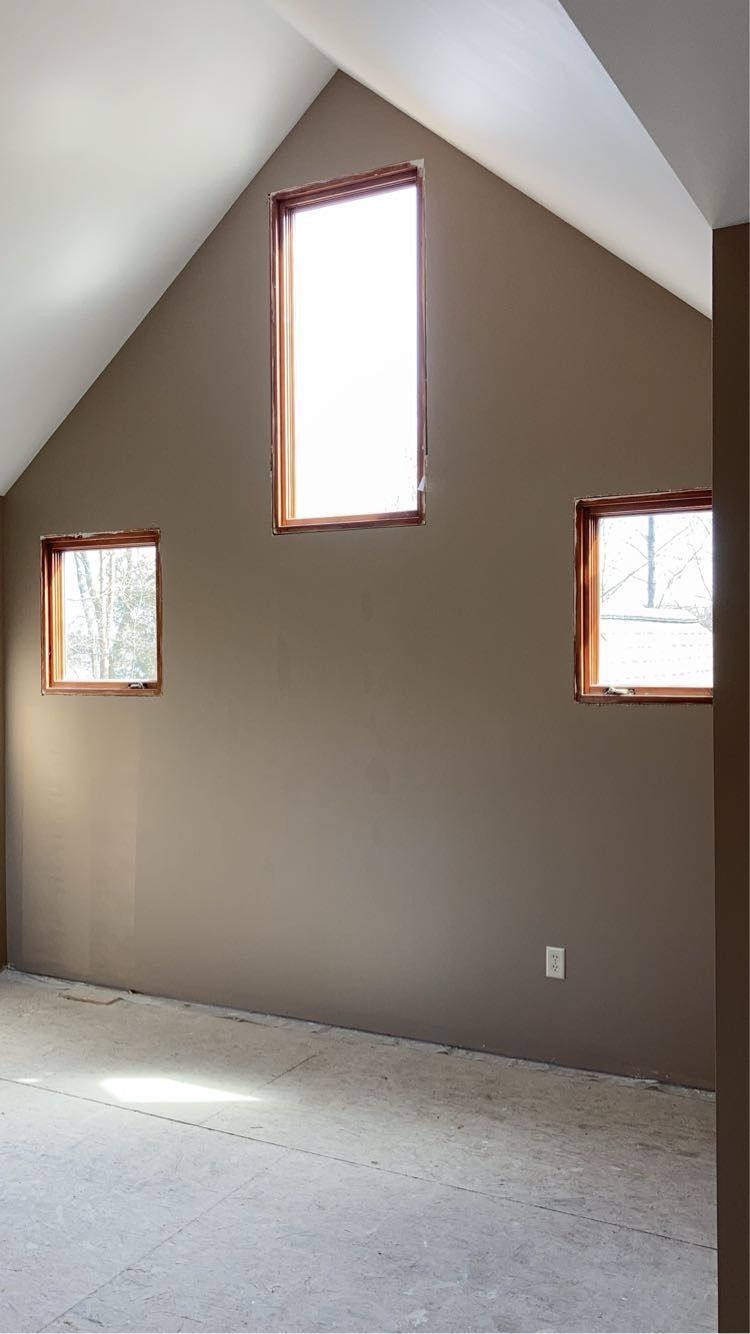 An empty room with a vaulted ceiling and three windows.