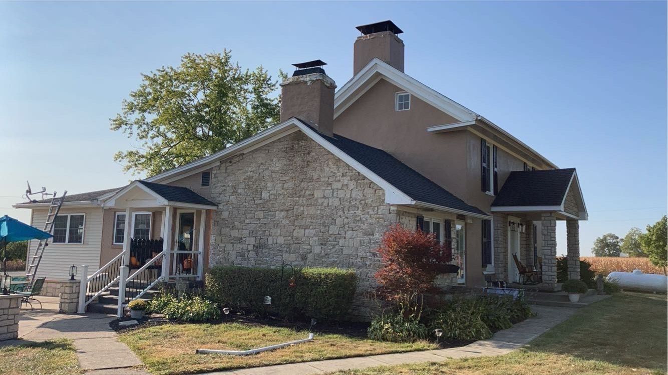 A house with a stone facade and a black roof