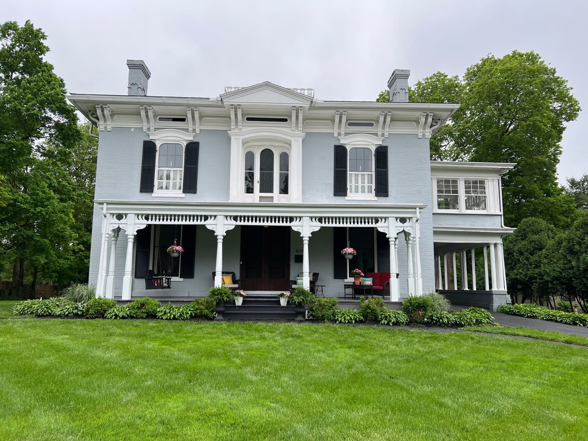 A large house with a porch and a large lawn in front of it