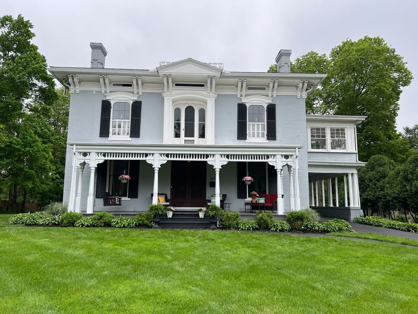 A large house with a porch and a large lawn in front of it