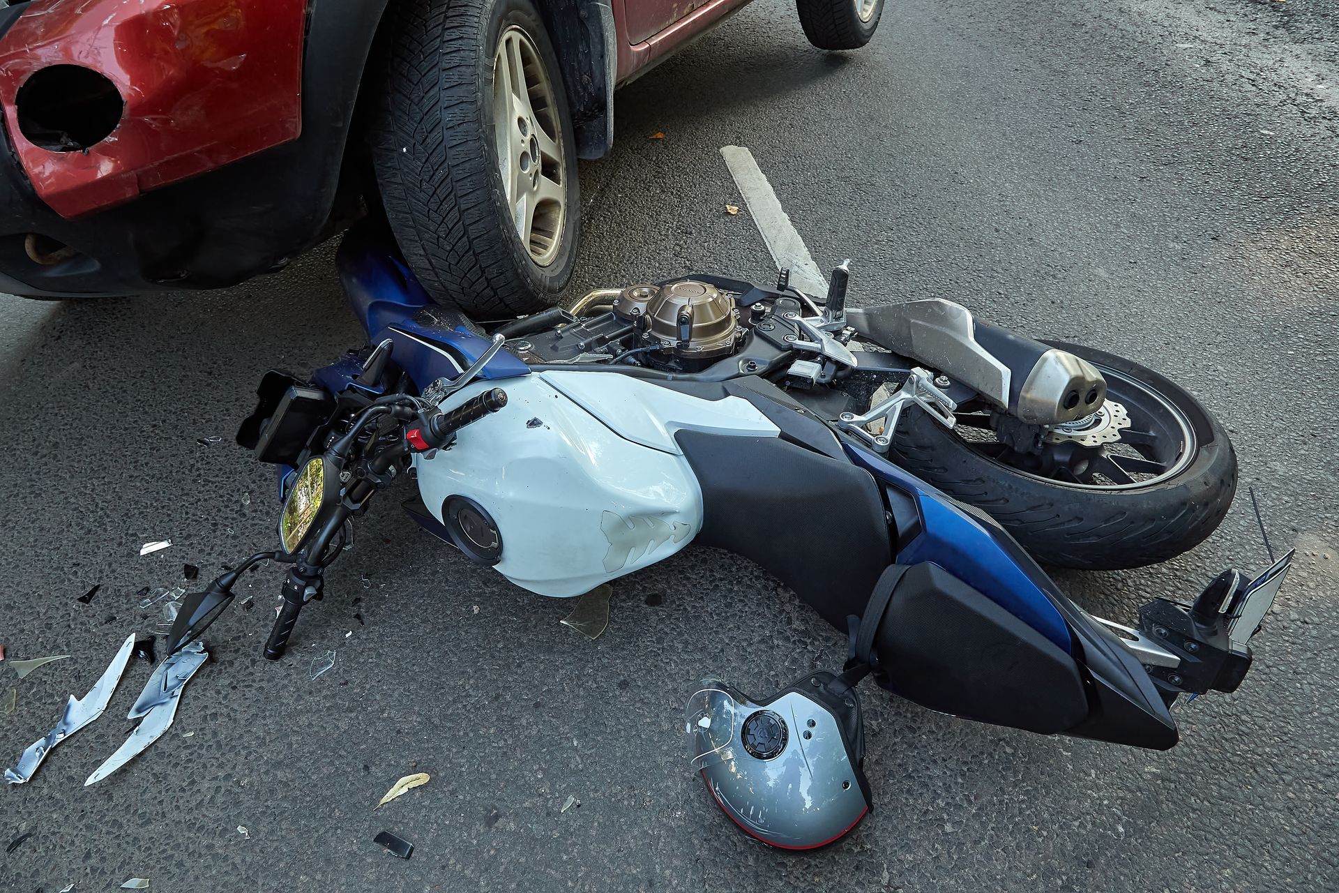 View of a damaged motorbike and a car after an accident. View of a damaged motorbike and a car after an accident.
