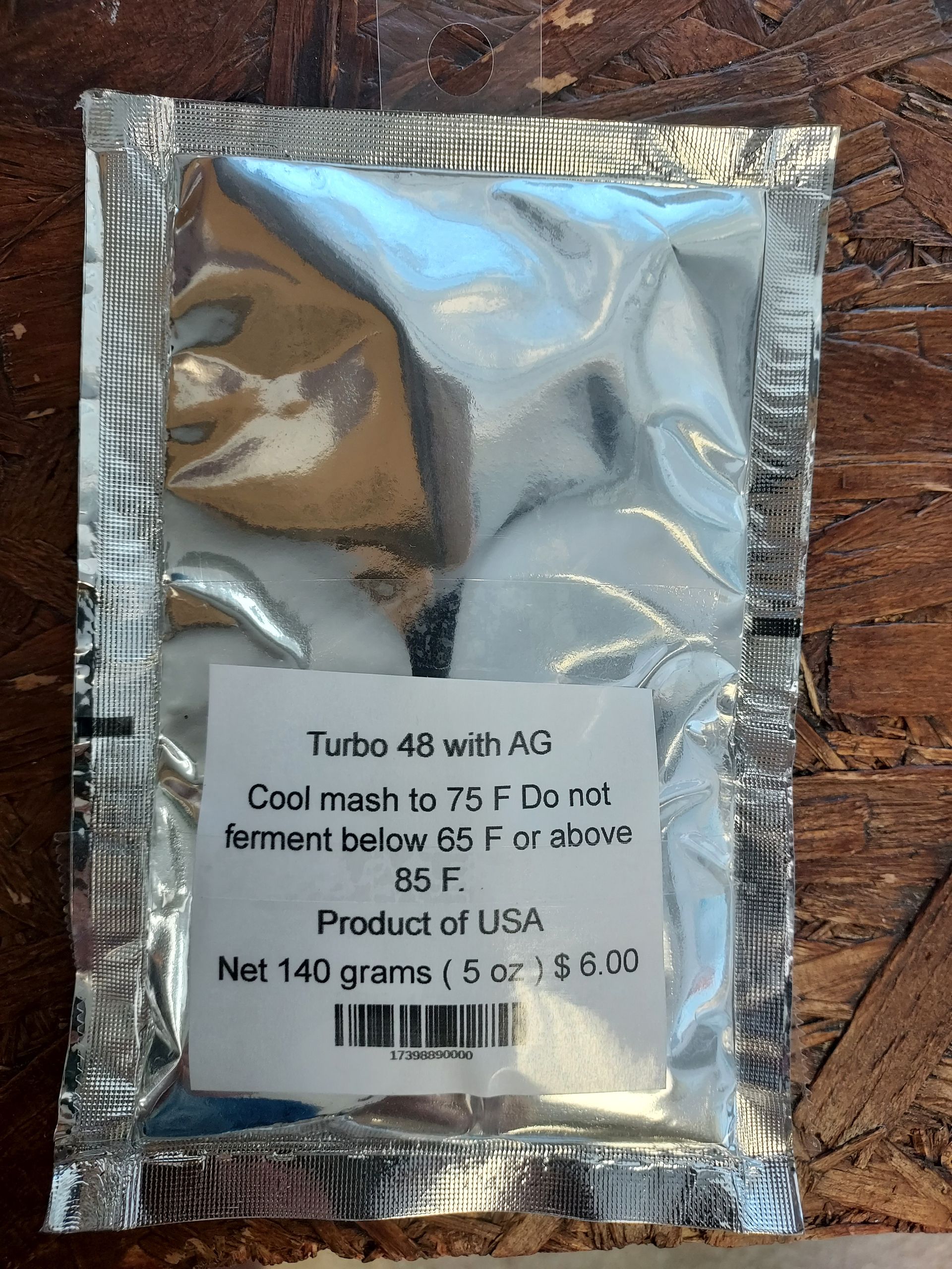 Silver foil packet with a white label and barcode, lying on a textured surface.