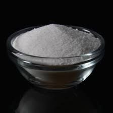 A glass bowl filled with white powder on a black background.