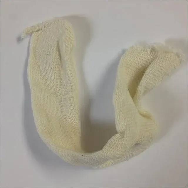 A white knitted scarf is sitting on a white surface.