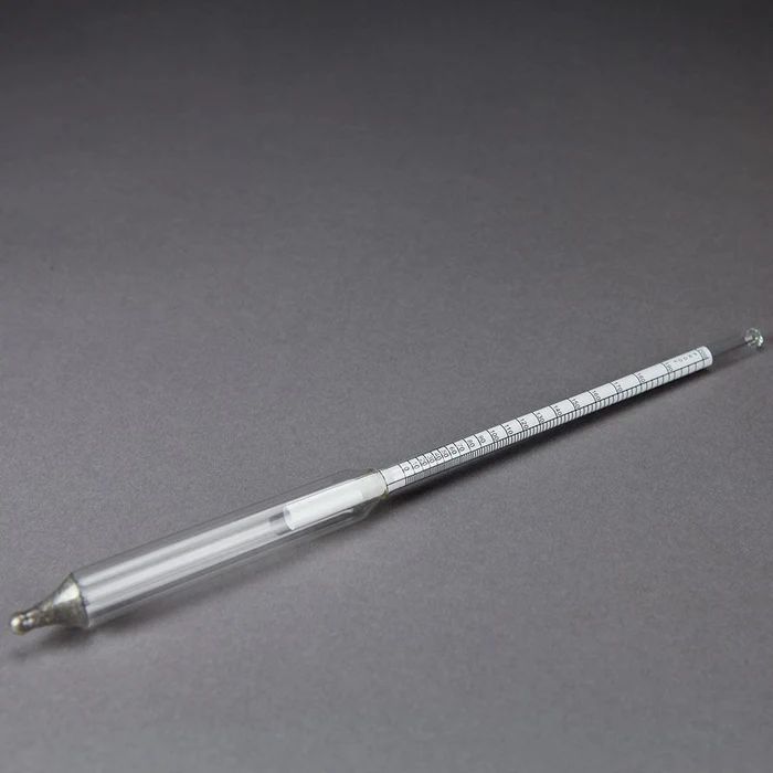 A glass thermometer is sitting on a gray surface