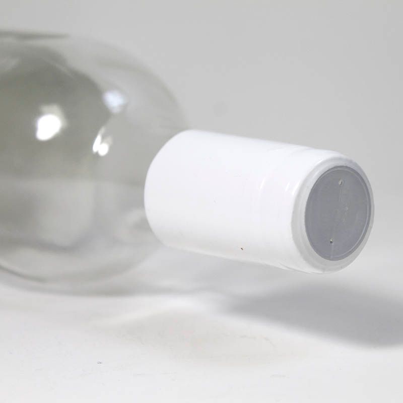 A close up of a bottle of wine with a white cap on a table.