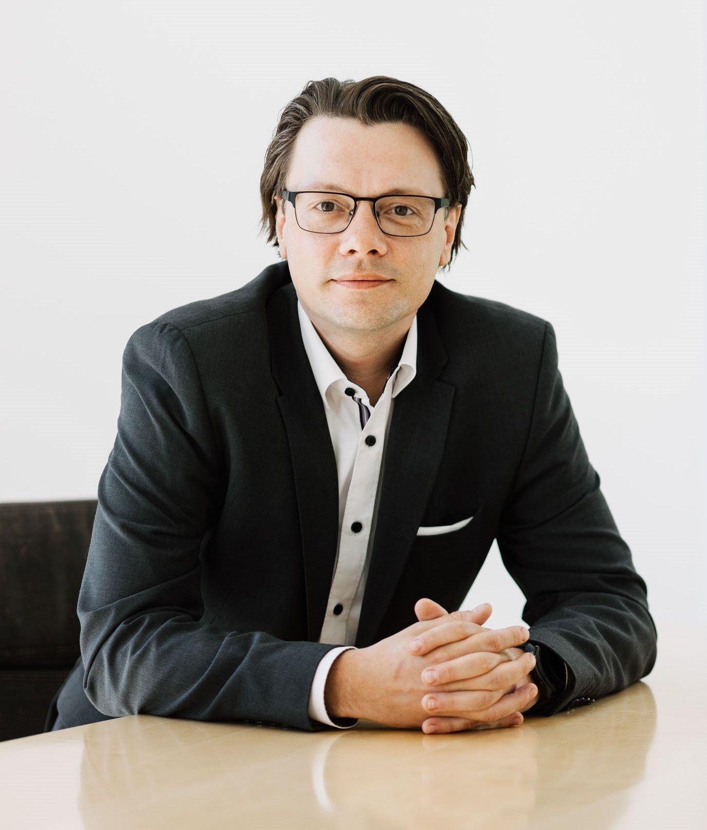 Professionelles Porträt von Alexander Kukovic – Finanzberater für Ärzte. Das Bild zeigt ihn im Anzug am Konferenztisch, freundlich und kompetent im Blick, vor heller Kulisse mit Tageslicht. Ideal für Blog, Website oder Autorenprofil: vertrauenswürdig, klar und nahbar.