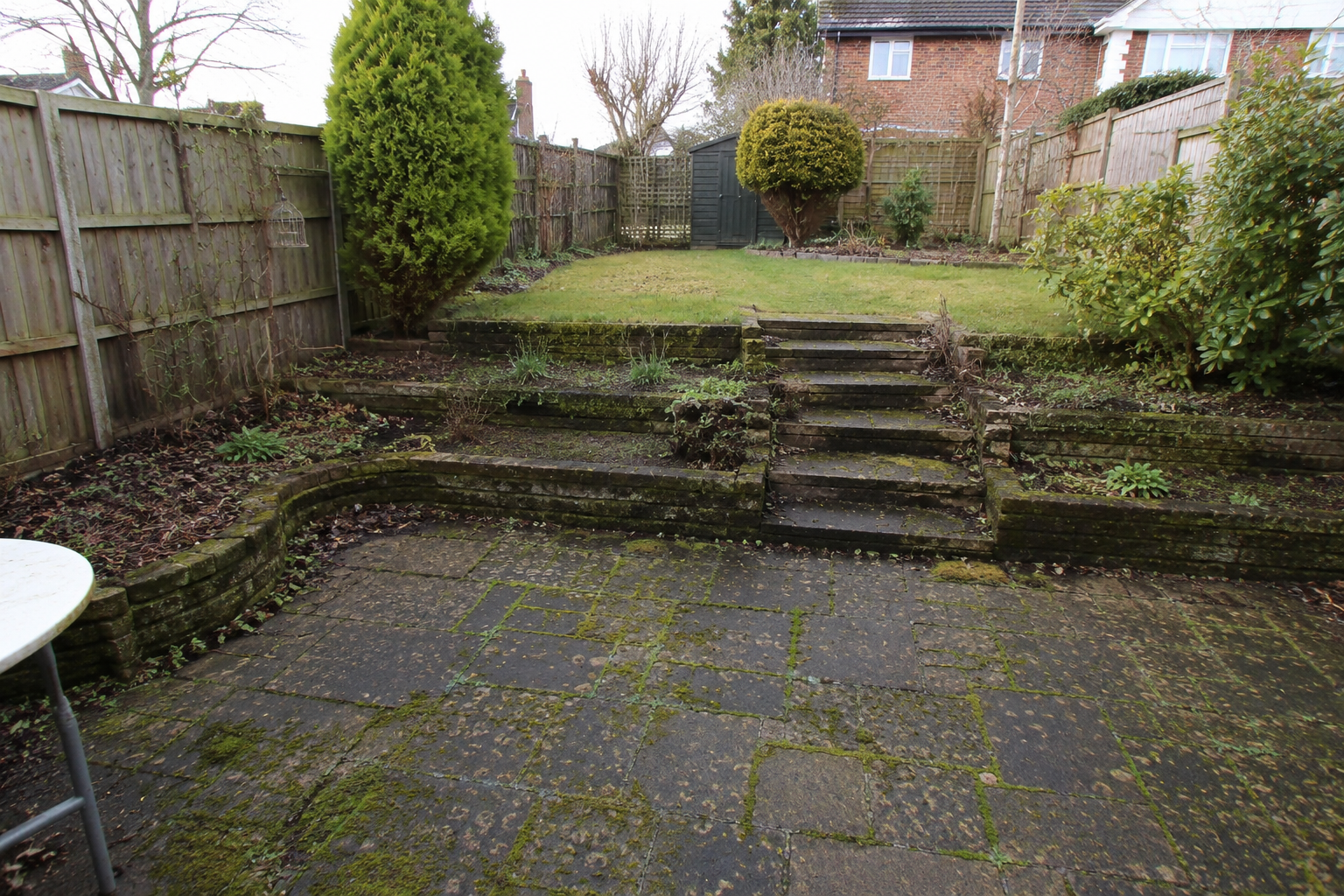Curved driveway lined with manicured shrubs leading to a large house with a steep roof.