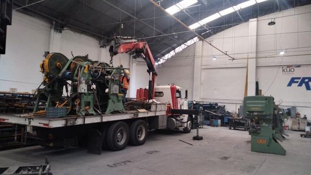 Una grúa levanta una máquina de un camión en un almacén.