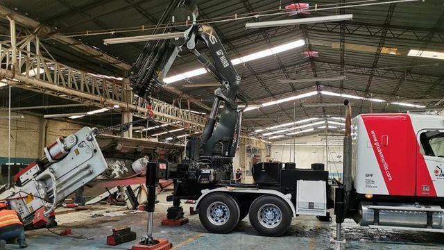 Un camión con una grúa adjunta está en un almacén.
