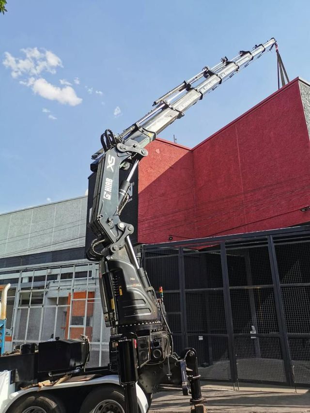 Una gran grúa está estacionada frente a un edificio rojo