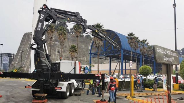 Un camión con una grúa acoplada está estacionado frente a un edificio.