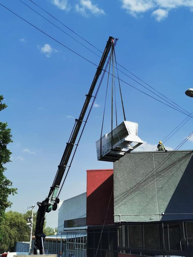 Una grúa levanta un gran objeto blanco sobre un edificio